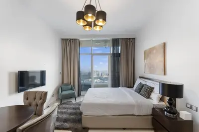 a bedroom with a bed and a desk and a tv at High-Floor Studio Ghalia JVC with an Amazing View in Dubai