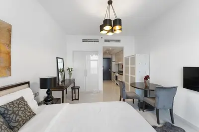 a bedroom with a white bed and a dining room at High-Floor Studio Ghalia JVC with an Amazing View in Dubai