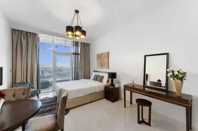 a bedroom with a bed and a desk with a mirror at High-Floor Studio Ghalia JVC with an Amazing View in Dubai