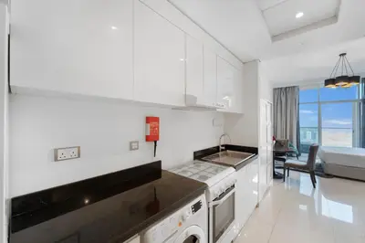 a kitchen with white cabinets and a stove top oven at High-Floor Studio Ghalia JVC with an Amazing View in Dubai