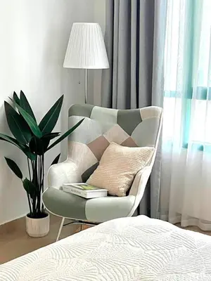 a bedroom with a chair and a lamp and a plant at Cozy 1BR Stay in Dubai Marina Near Beach and Tram in Dubai