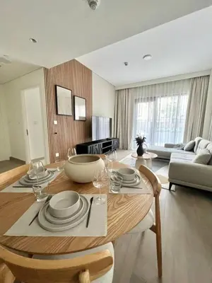a living room with a table with plates and wine glasses at Luxury 1BR with Huge Terrace with Creek Beach Lagoon in Dubai