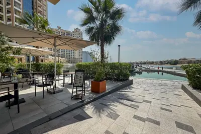 a patio with a table and chairs and a palm tree at Luxury Upgraded Palm Studio with Marina and Yacht Views in Dubai