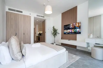 a bedroom with a white bed and a tv on the wall at Modern Studio in Peninsula One with Canal Views in Dubai