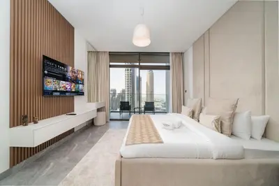 a bedroom with a large white bed and a tv at Modern Studio in Peninsula One with Canal Views in Dubai
