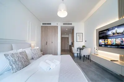 a bedroom with a white bed and a dining room at Luxury Studio in Peninsula One, Bay Views in Dubai