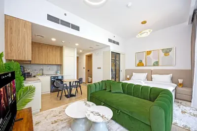 a living room with a green couch and a kitchen at Chic Living in Meraki comfy studio in Dubai