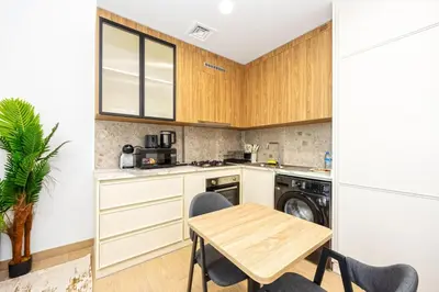 a kitchen with a wooden table and a small table and chairs at Chic Living in Meraki comfy studio in Dubai