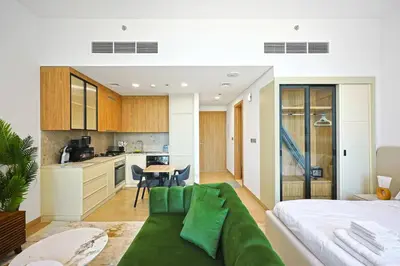 a living room with a green couch and a kitchen at Chic Living in Meraki comfy studio in Dubai