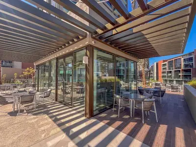 a covered patio with tables and chairs and windows at Frank Porter - Peninsula Five, Business Bay in Dubai