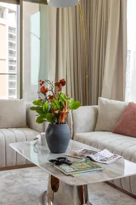 a living room with a table with a vase on it at Frank Porter - Peninsula Five, Business Bay in Dubai