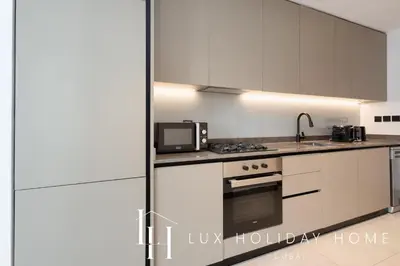 a kitchen with white cabinets and a microwave at LUX The 15 Northside Burj Khalifa View Suite in Dubai