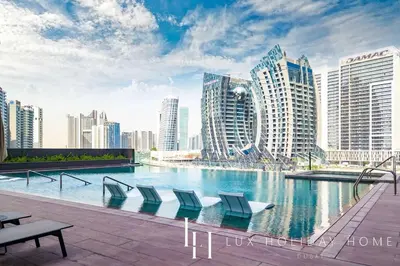 a pool with chairs and buildings in a city at LUX The 15 Northside Burj Khalifa View Suite in Dubai