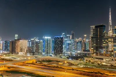 a city skyline at night with traffic on a freeway at Savis Homes - Stylish 1BR in Business Bay with Burj Khalifa View in Damac Paramount Tower in Dubai