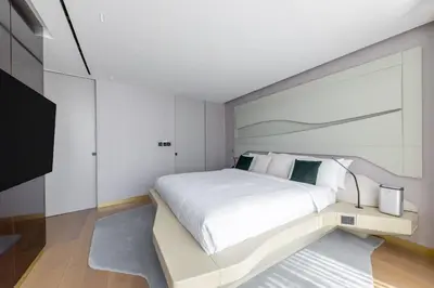 a white bedroom with a large white bed and a tv at The Opus residences 1 bedroom city view in Dubai