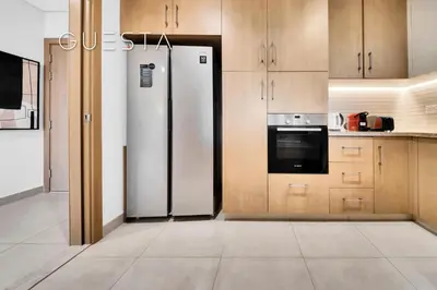 a kitchen with a refrigerator and wooden cabinets at Vida Residences The Hills, Dubai in Dubai