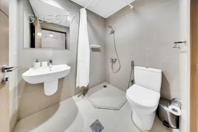 a white bathroom with a toilet and a sink at Vida Residences The Hills, Dubai in Dubai