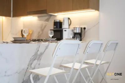 a group of white chairs sitting at a counter in a kitchen at Splendour Living 1BR at Azizi Riviera in Dubai