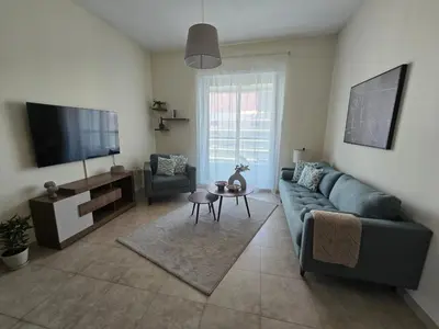 a living room with a couch and a flat screen tv at Dar Al Noor Apartment in Dubai