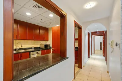 a kitchen with wooden cabinets and a hallway at Luxe 3BR and Maid Room with Panoramic Dubai Eye View - JBR Beach in Dubai