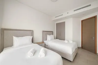 two beds in a hotel room with white sheets at FIRST CLASS 2BR Luxury Living at Waves Grande in Dubai