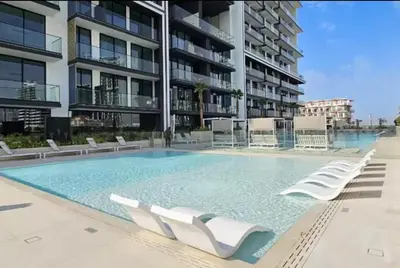 a large swimming pool with white chairs in front of a building at FIRST CLASS 1BR Minimalist Elegance in Dubai