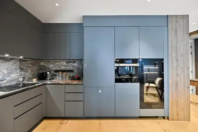 a kitchen with white cabinets and a blue wall at Prestigious 2BD Seaside Apartment, The Address JBR in Dubai