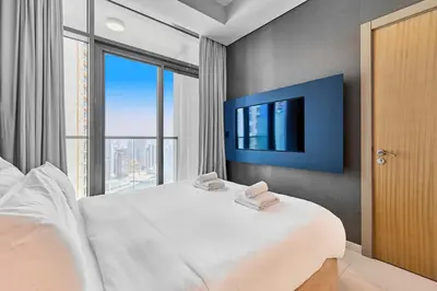 a bedroom with a large bed with a tv on the wall at Luxury 2BR with Skyline Views Prime Business Bay Location in Dubai