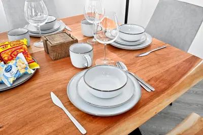 a wooden table with plates and wine glasses on it at Torch Dubai Marina 2BDR with Pool Gym and Views in Dubai
