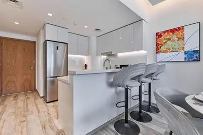 a kitchen with a bar with stools and a refrigerator at Luxury 1BR in Central Business Bay in Dubai
