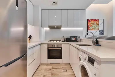 a white kitchen with a washer and dryer at Luxury 1BR in Central Business Bay in Dubai