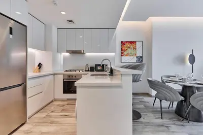 a kitchen with white cabinets and a table with chairs at Luxury 1BR in Central Business Bay in Dubai