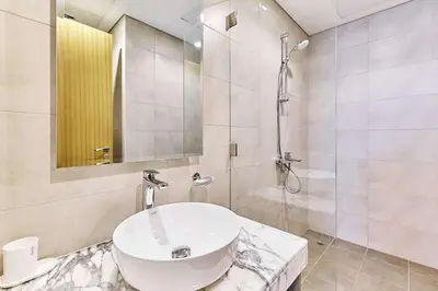 a white bathroom with a sink and a shower at Elegant 2BR Apartment Heart of Business Bay High Floor in Dubai