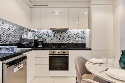 a kitchen with white cabinets and a table with chairs at Elegant 2BR Apartment Heart of Business Bay High Floor in Dubai