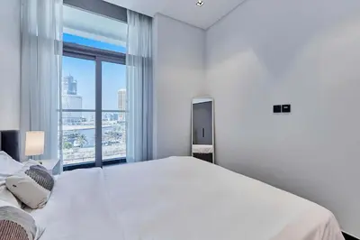 a white bedroom with a large bed and a large window at Khalifa View Luxe 1BHK in Dubai