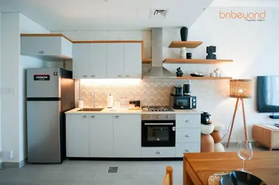 a kitchen with white cabinets and a refrigerator at Nomad Haven with Pvt Cinema and C0-working Space in Dubai