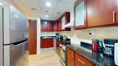 a kitchen with wooden cabinets and a stainless steel refrigerator at Vacationer I Luxury 2 Bedroom Apartment I Marina View I Steps from JBR Beach in Dubai