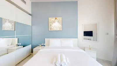 a bedroom with a white bed and a blue wall at Vacationer l 1 Bedroom Perched on the 19th Floor l Free Pool, Gym Access in Dubai