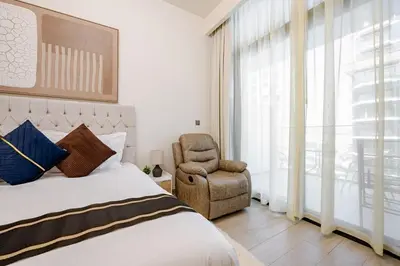 a bedroom with a bed and a chair and a window at Ramaira Homes Azizi Riviera 26 by Vacay Xeal in Dubai