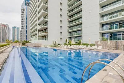 a large swimming pool with chairs and buildings at Modern 1BR Near Burj Khalifa Business Bay Reva Apt in Dubai