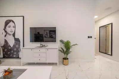 a white bathroom with a sink and a picture of a woman at Stylish 1BR Just 3 Minutes Walk to Metro in Dubai