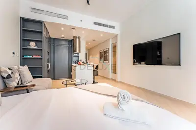 a bedroom with a large bed and a living room at Studio Near Ras Al Khor Wildlife Sanctuary with Partial Creek Views, Just Minutes from Downtown Attractions, Wilton Park Residences, Sobha Hartland by Deluxe Holiday Homes in Dubai