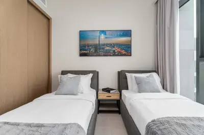two beds in a hotel room next to a table at Elegant 3BR & City Skyline View Azizi Greenfield in Dubai