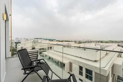 a chair on a balcony with a view of a city at Elegant 3BR & City Skyline View Azizi Greenfield in Dubai