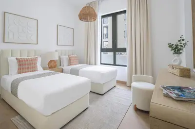 a white bedroom with two beds and a table at Frank Porter - La Sirene, Jumeirah in Dubai