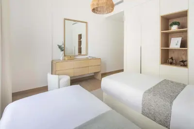 a white bedroom with two beds and a mirror at Frank Porter - La Sirene, Jumeirah in Dubai