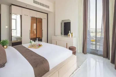 a white bedroom with a large bed and a tv at Frank Porter - GEMZ by Danube, Al Furjan in Dubai
