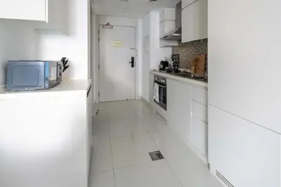 a kitchen with white cabinets and a tv on the counter at Frank Porter - The Vogue, Business Bay in Dubai