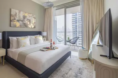 a bedroom with a bed and a television and a balcony at Frank Porter - Palace Beach Residence Tower 1 in Dubai