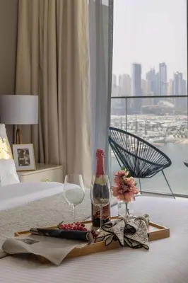 a tray with a bottle of wine and glasses on a bed at Frank Porter - Palace Beach Residence Tower 1 in Dubai